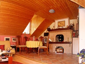 A cozy attic room with a brick fireplace, wooden ceiling, and a dining table set for four.