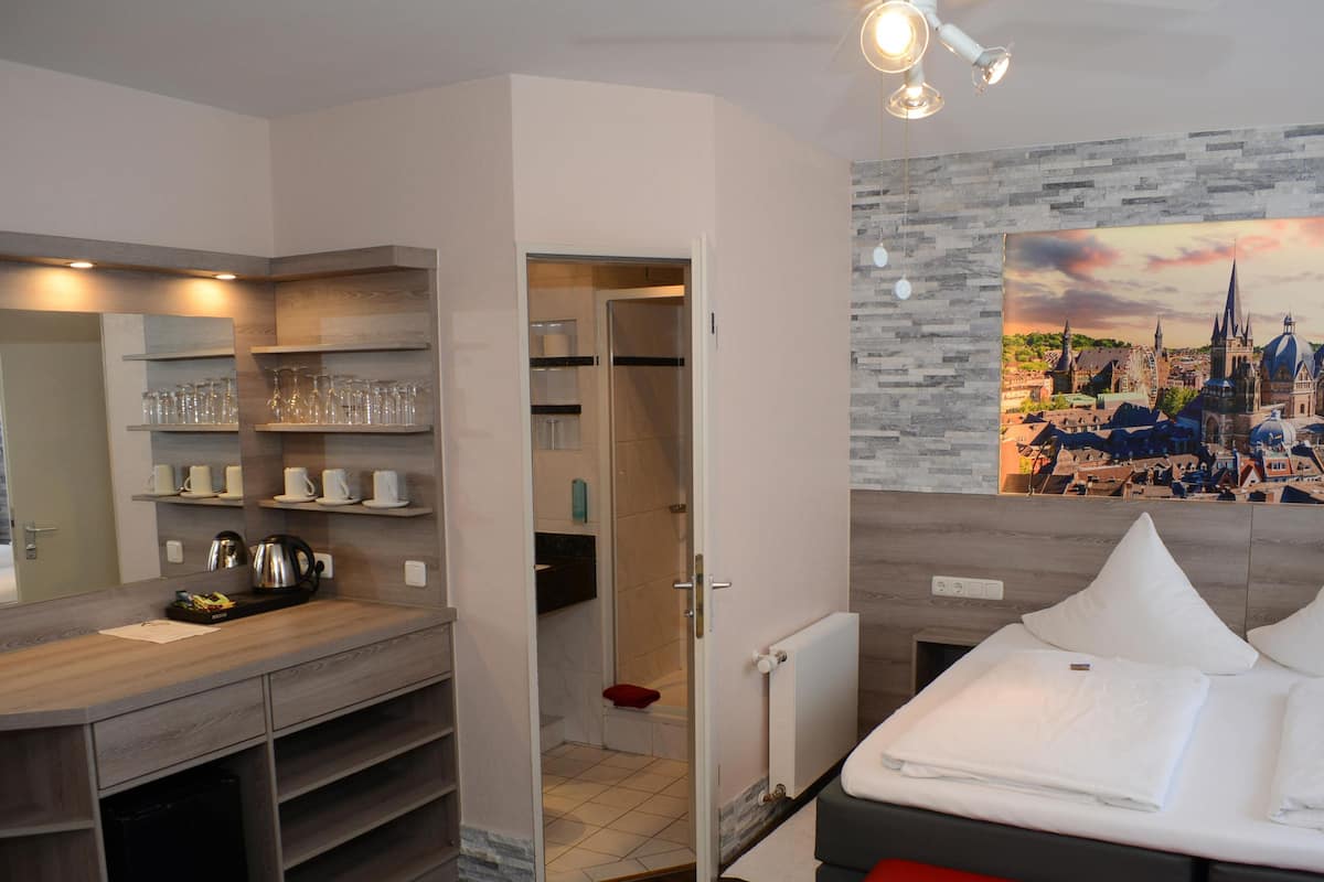 A modern bedroom with a bed, a red bench, a ceiling fan, and a cityscape mural on the wall.