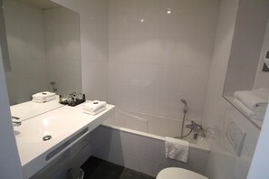 A modern bathroom with a white sink, a bathtub, and a toilet.