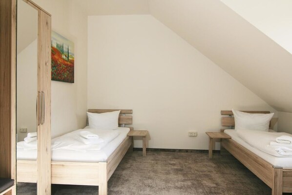 Un hotel pequeño con una sola habitación, dos camas de madera, un armario de madera y un cuadro en la pared.