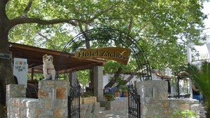 Um portão de entrada de pedra com uma placa indicando 'Hotel Zachos'.