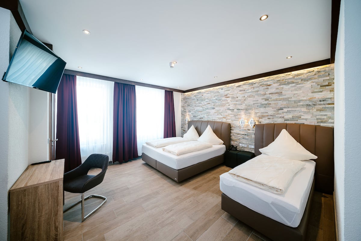 A modern hotel room with two beds, a desk, and a TV.
