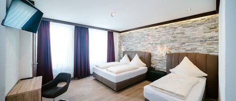 A modern hotel room with two beds, a desk, and a TV.