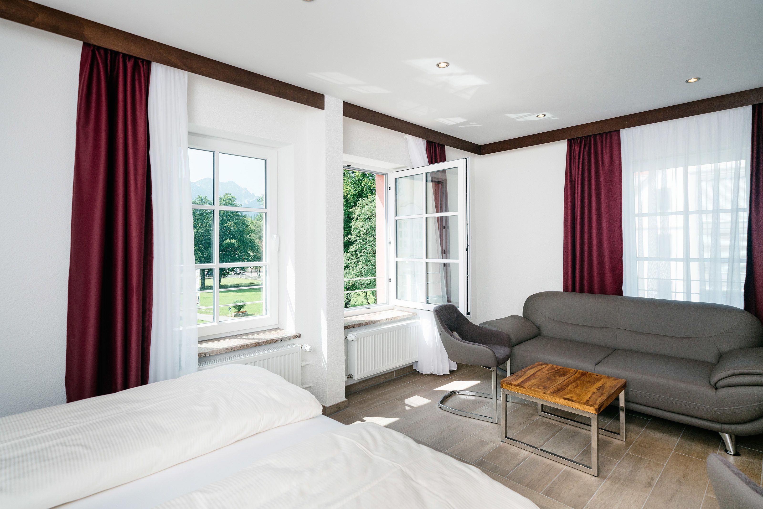 Una habitación moderna con un sofá gris, una mesa de centro de madera y una cama.
