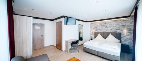 Una habitación de hotel moderna con cama, escritorio, sofá y una pequeña mesa de madera.