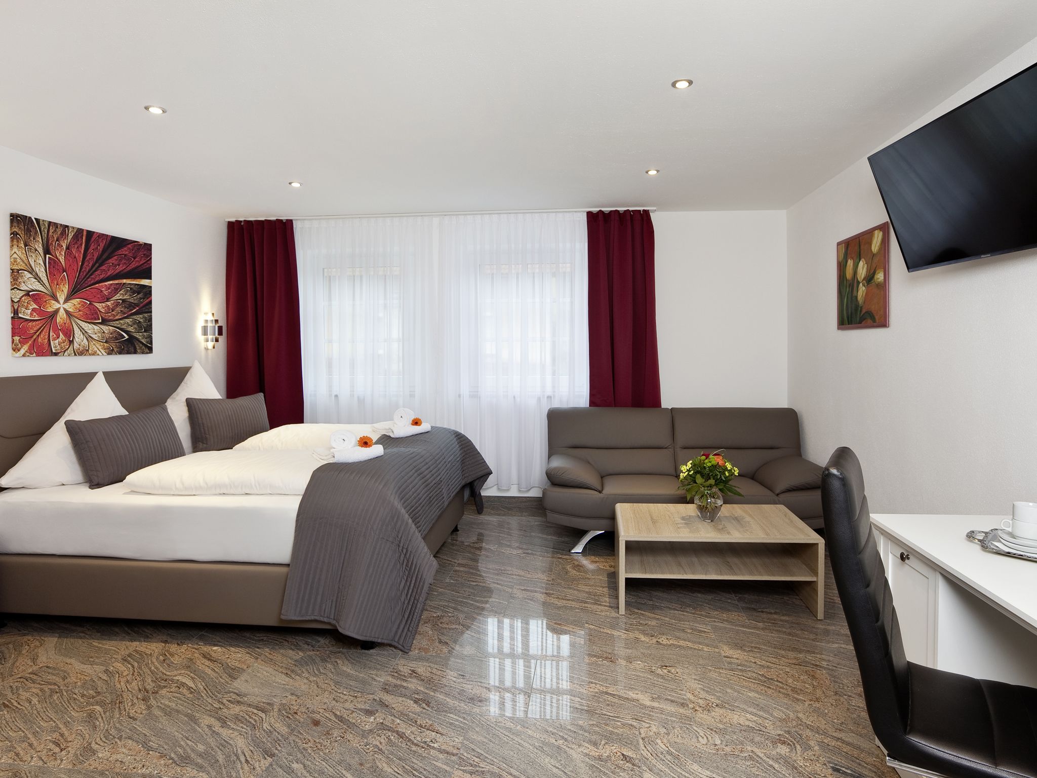 Une chambre d’hôtel moderne équipée d’un lit, d’un canapé, d’une table basse et d’un téléviseur.