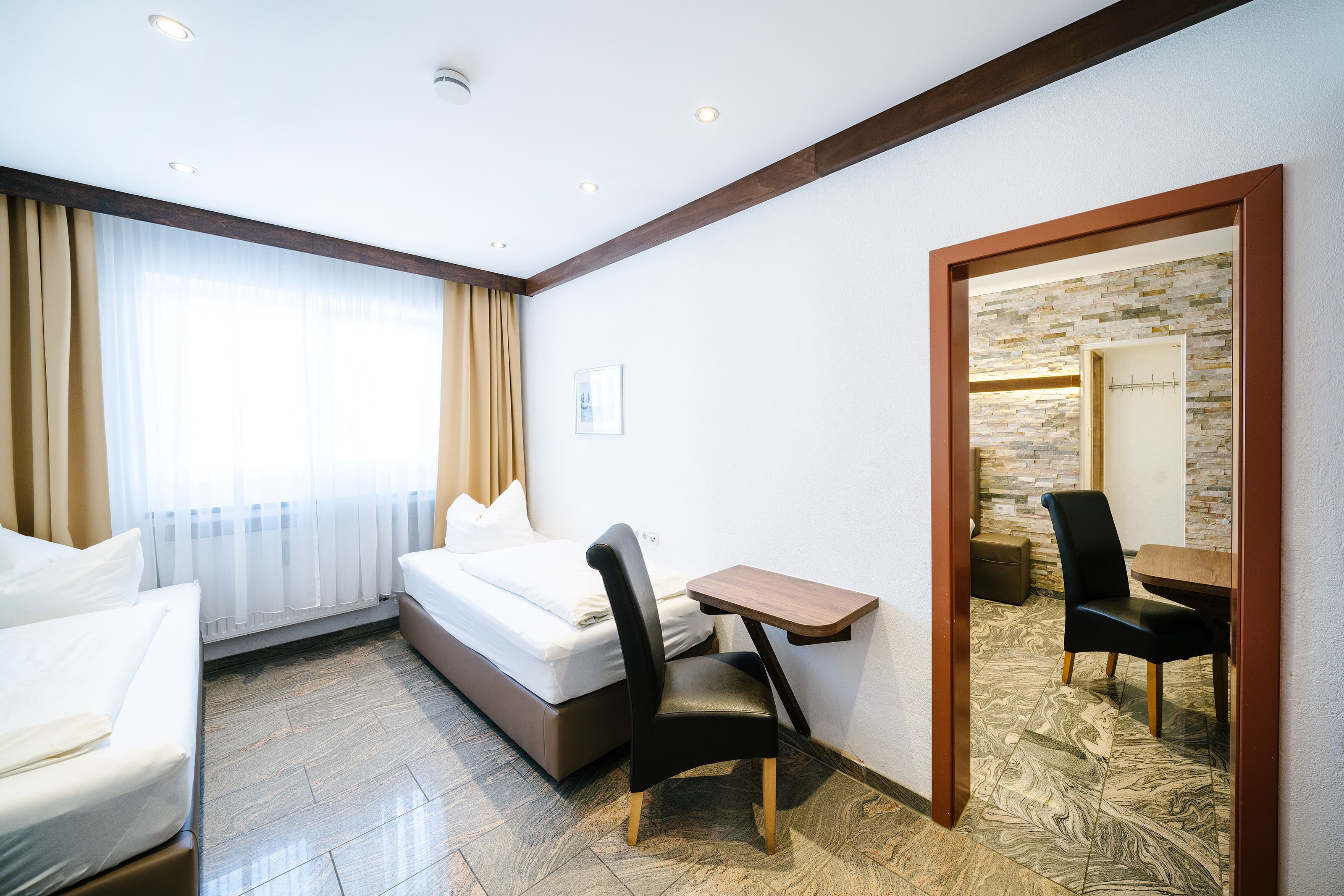Une chambre d’hôtel avec un lit, un bureau, une chaise et une petite table.