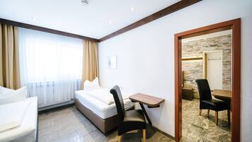 Une chambre d’hôtel avec un lit, un bureau, une chaise et une petite table.