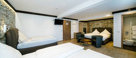 A modern hotel room with two single beds, a small desk, and a shower area.