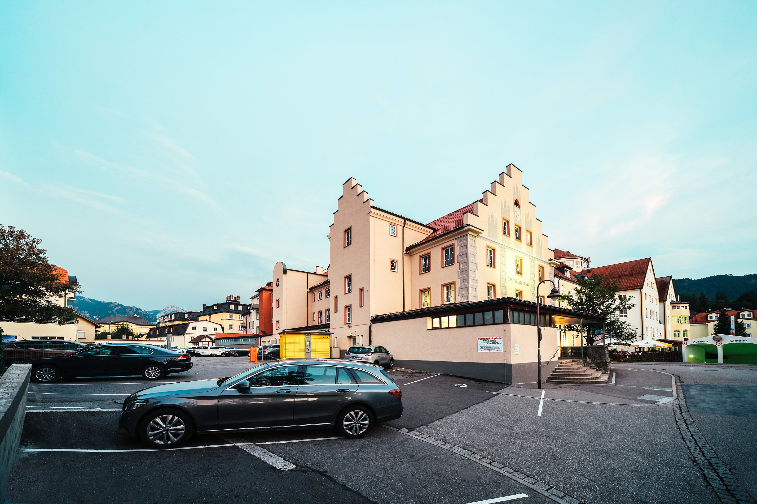 Straßenansicht eines Gebäudes mit markanter Architektur, einem Parkplatz und blauem Himmel.