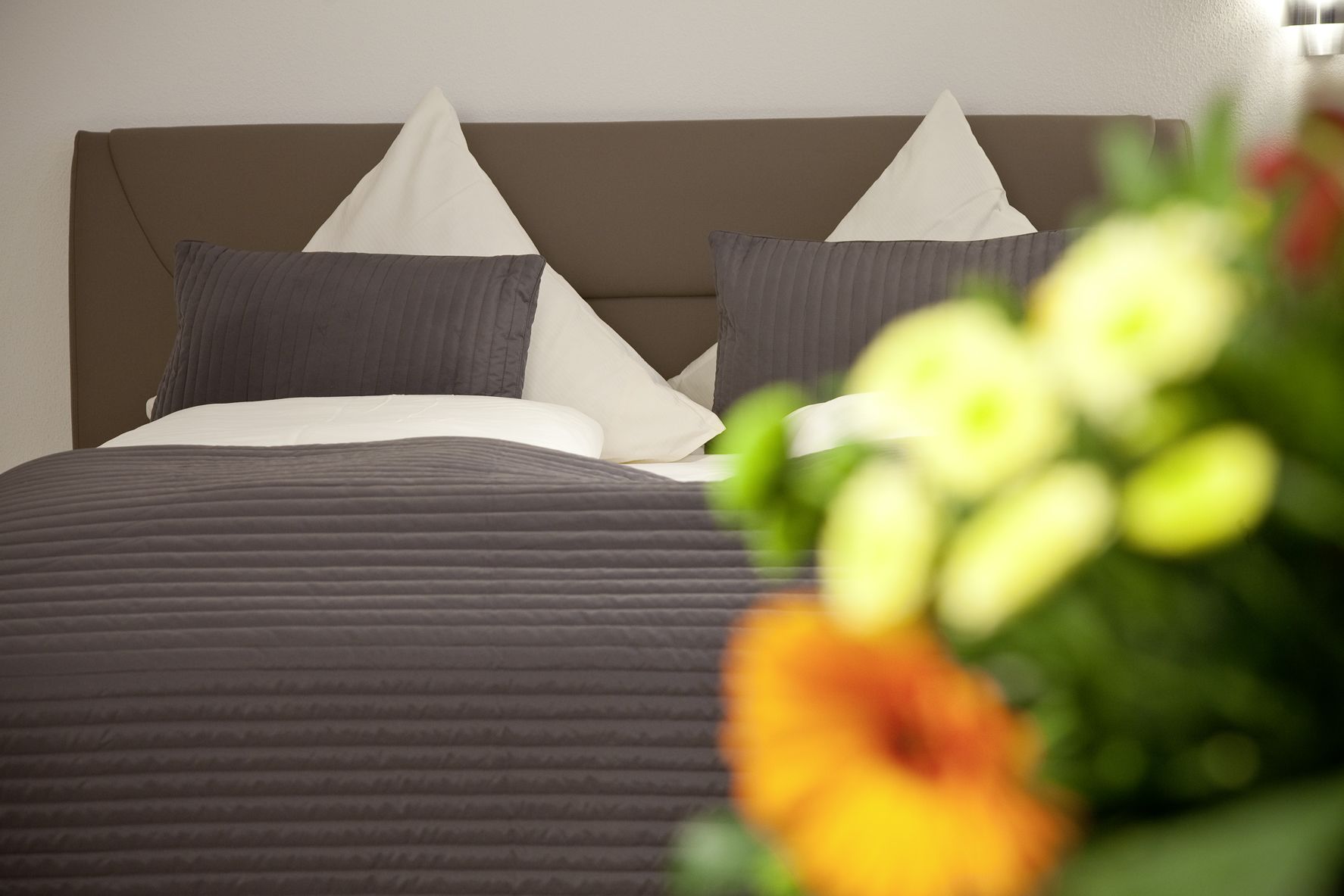 A hotel room with a bed, pillows, and a nightstand.