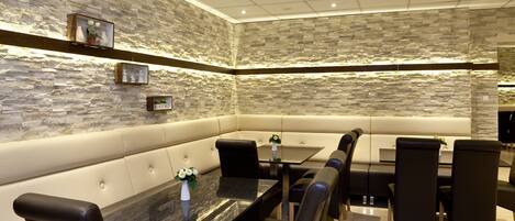 A modern dining area with a stone wall, cushioned seating, and a marble table.