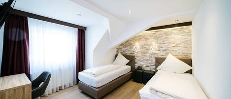 Una habitación de hotel moderna con una cama, un escritorio, una silla y una pared decorativa de piedra.