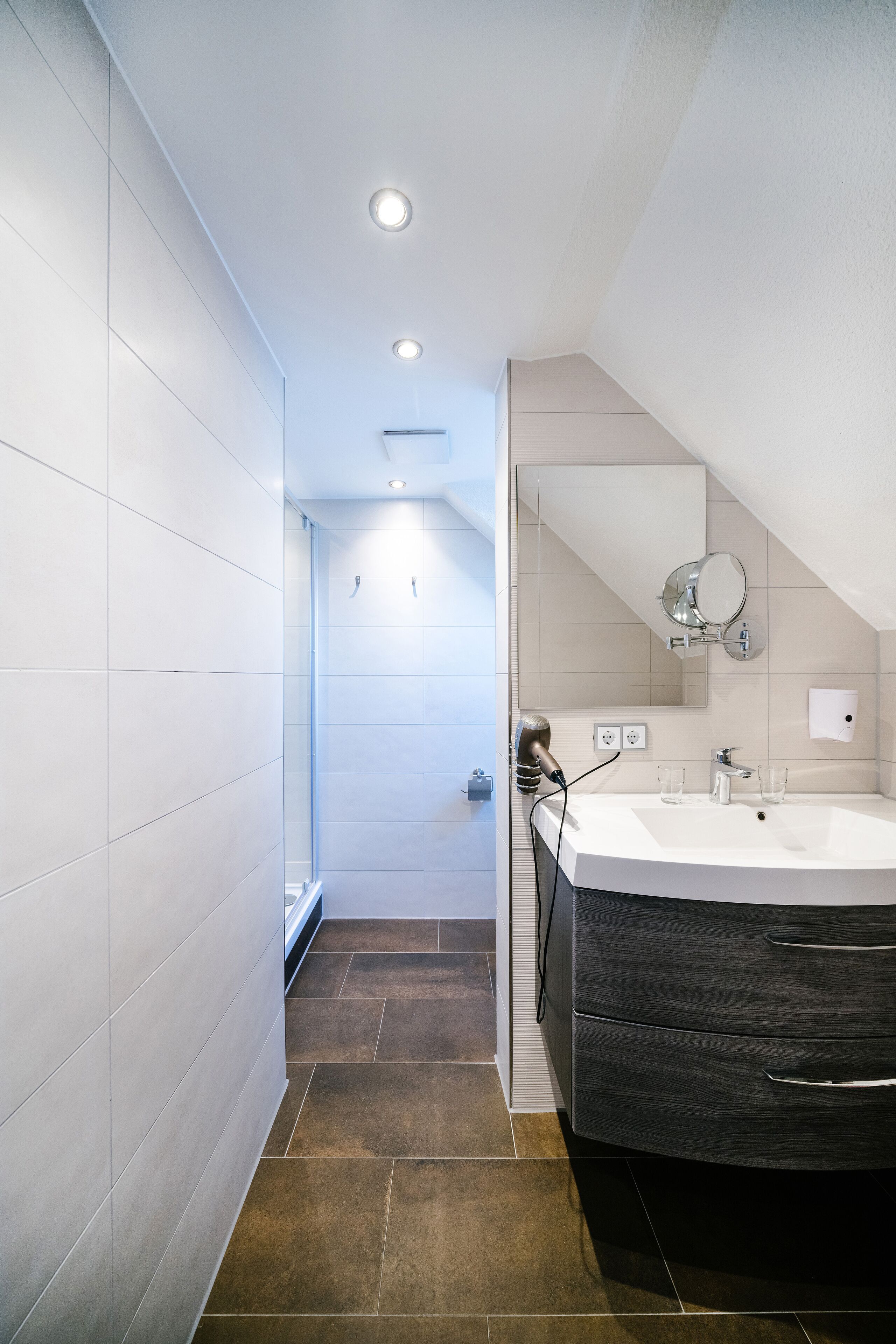 Une salle de bain moderne avec un grand lavabo, un miroir et une douche.