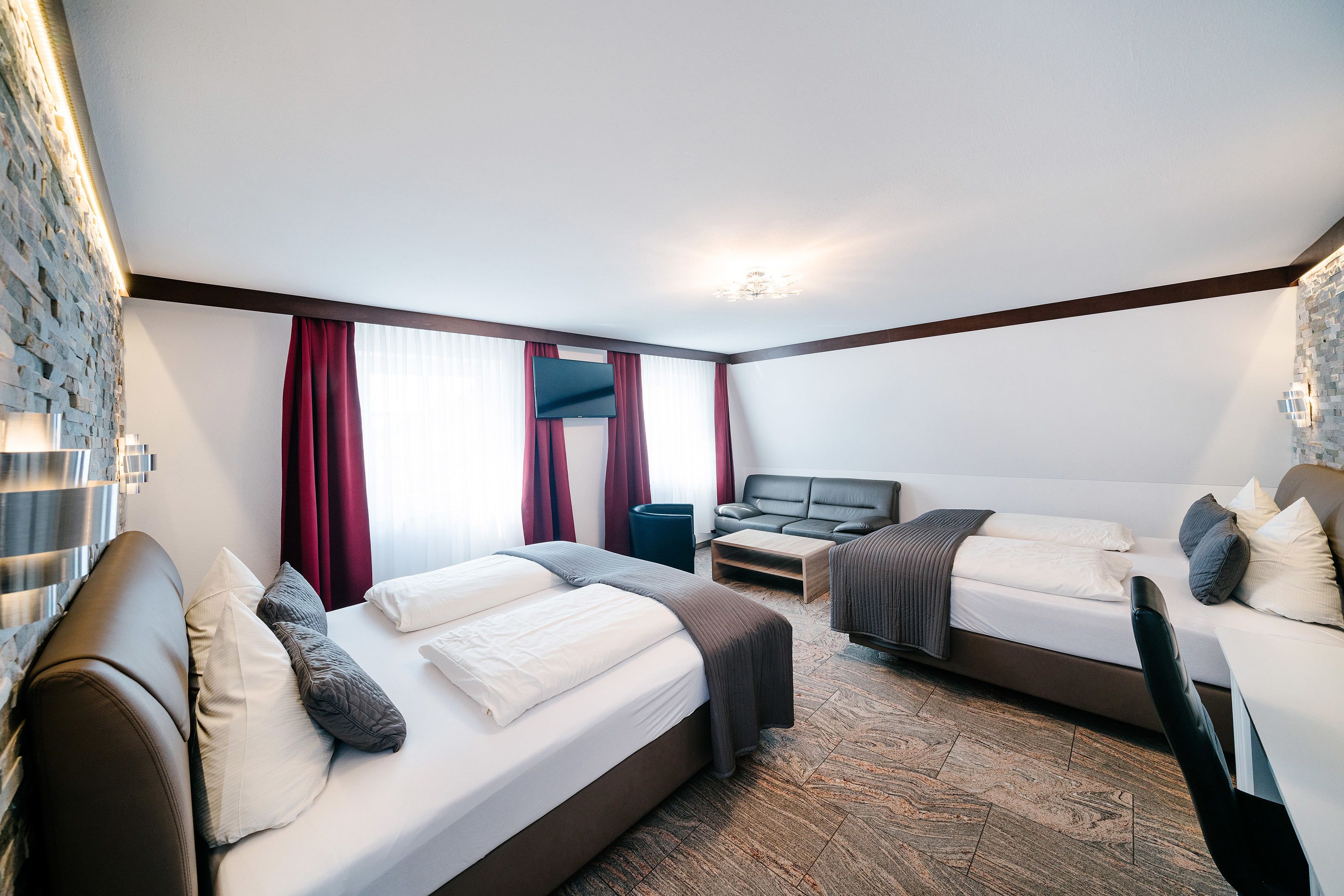 Une chambre d’hôtel moderne avec deux lits, un canapé et une télévision.