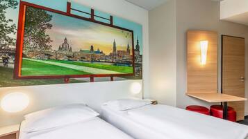 Ein Hotelzimmer mit einem Bett, einem Nachttisch, einer Wandlampe und einem Stadtbild.