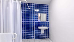 Une salle de bain avec un rideau de douche, un lavabo et un miroir.