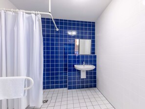 A bathroom with a shower curtain, a sink, and a mirror. - B&B HOTEL Dresden-Messe (Dresden)