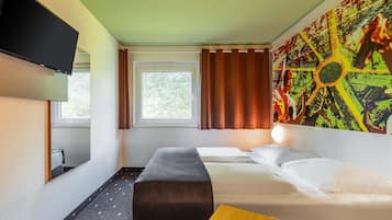 A hotel room with a bed, a desk, a TV, a window with curtains, and a large abstract painting on the wall.