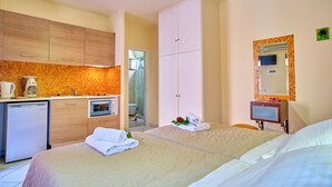 Habitación de hotel con kitchenette, cama con toallas, baño y espejo.