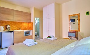 Habitación de hotel con kitchenette, cama con toallas, baño y espejo.
