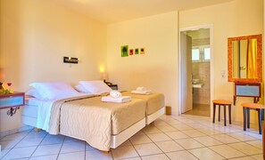 A hotel room with two beds, a desk with a lamp, a bathroom visible through an open door, and a mirror with a yellow curtain. - Chrismos Luxury Suites & Studios (Corfu)