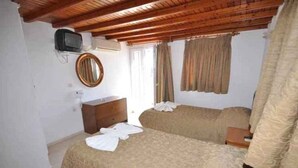 Un dormitorio con techo de madera, una cama con colcha color beige, una mesita de noche, un espejo y un televisor en la pared.