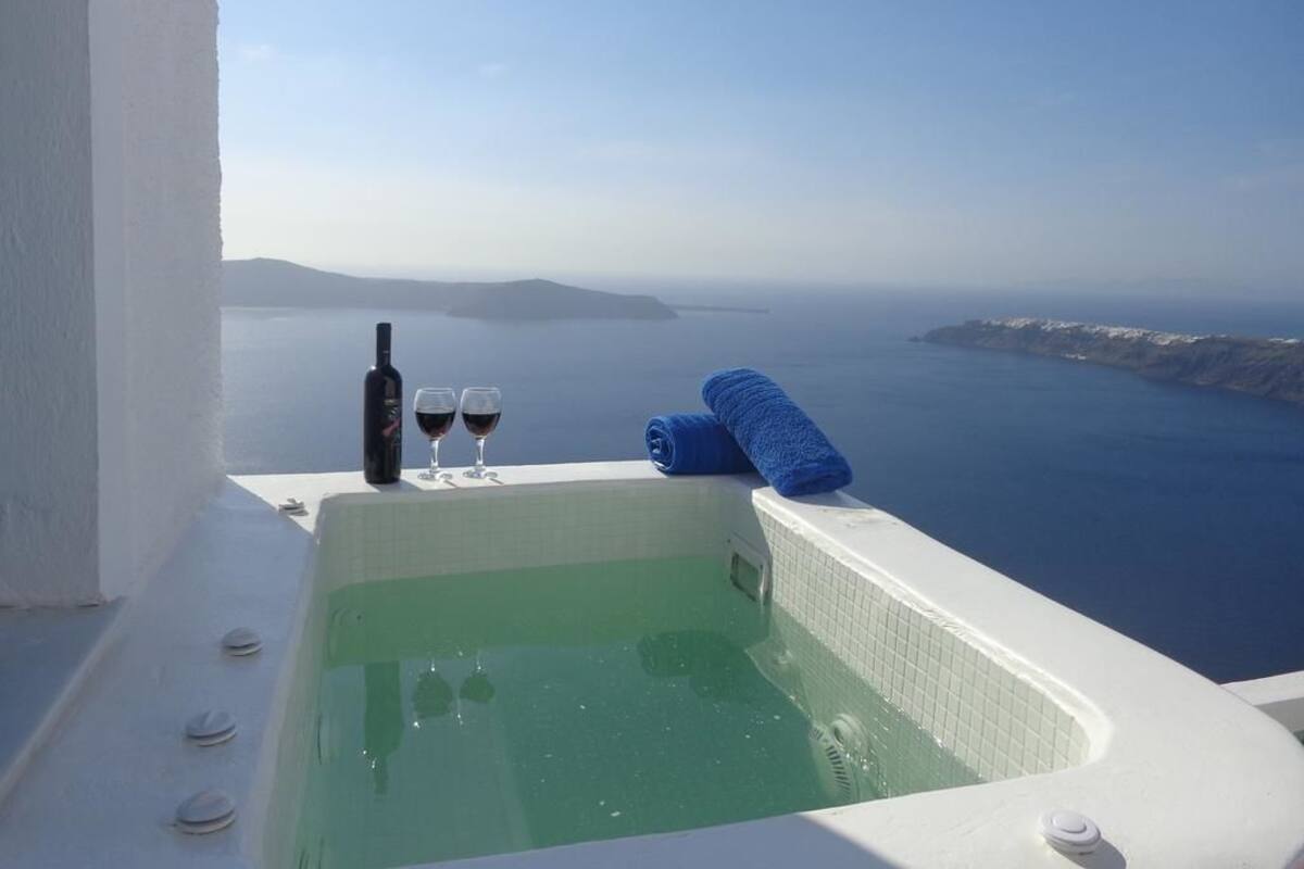 Un jacuzzi con vista al mar, una botella y vasos.