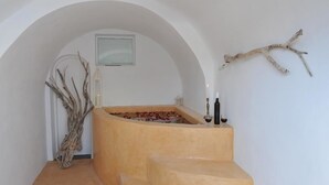 Un área de spa con una bañera, una rama decorativa y una vela.