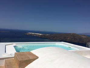 A pool with a clear view of the ocean and a rocky coastline. - Langas Villas (Santorini)