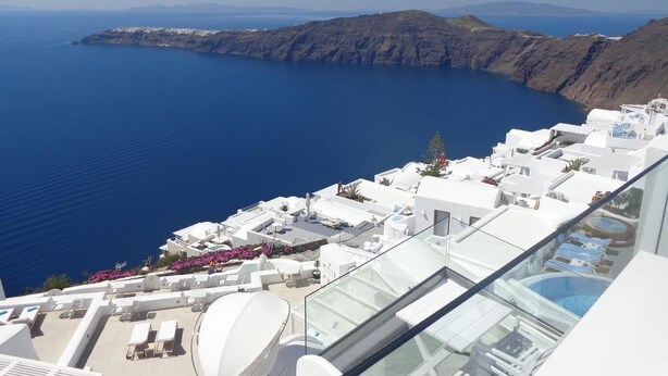 Un hotel costero con edificios blancos, una piscina y vistas al mar y acantilados.