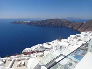 A coastal hotel with white buildings, a pool, and a view of the sea and cliffs. - Langas Villas (Santorini)