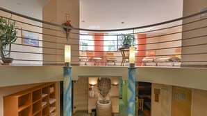 A hotel lobby with a curved ceiling, a reception desk, and a seating area with chairs and a table. - Hotel Weinbauer (Schwangau)