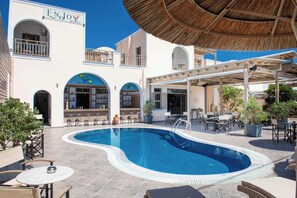 A hotel with a swimming pool, outdoor seating, and a bar.