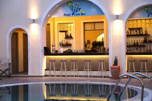 A poolside bar area with a pool, bar stools, and a sign reading "Pool Cafe Bar". - Enjoy Villas (Santorini)