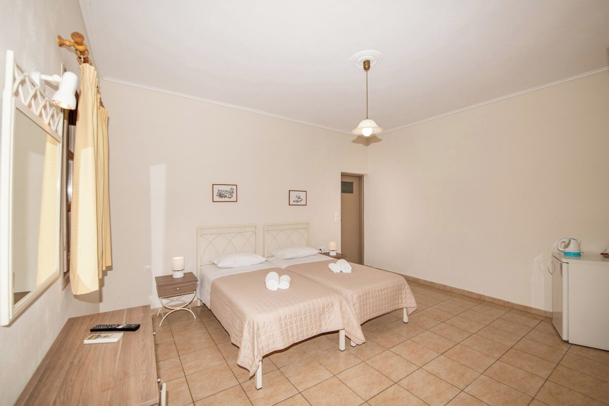 A hotel room with a bed, bedside tables, a desk, a chair, a wardrobe, and a ceiling light.