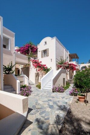 A white building with a stone pathway and pink flowers.
