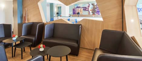 Un moderno área de lounge con sofás de cuero y mesas, un mostrador de recepción y una pared de acento de madera.