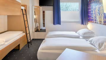 Een hotelkamer met twee bedden, een houten bureau, een ladder, een raam met gordijnen en een schilderij aan de muur.