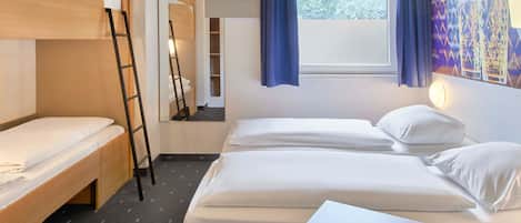 Habitación de hotel con dos camas, un escritorio de madera, una escalera, una ventana con cortinas y un cuadro en la pared.