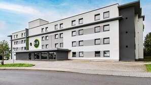 A modern hotel building with a flat facade, multiple windows, and a logo on the front.