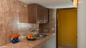 A kitchen with brown cabinets, a sink, and a fruit bowl on the counter.