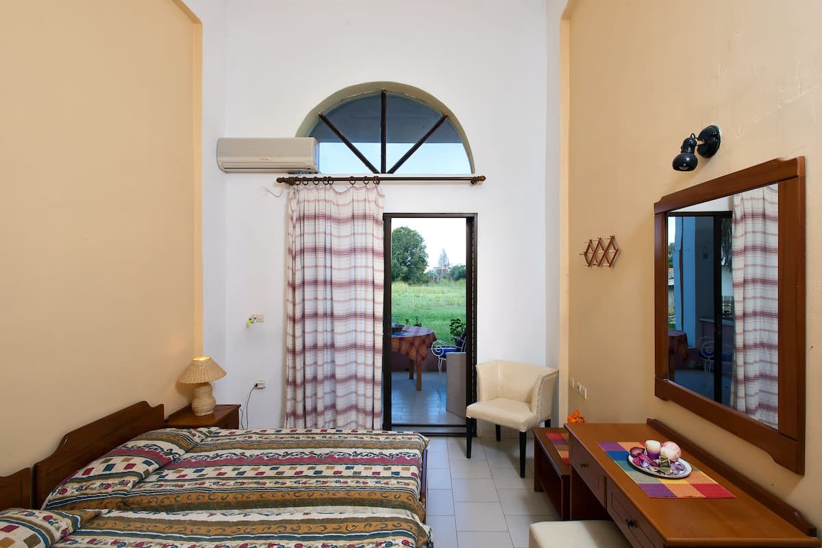 A bedroom with a bed, a chair, a table with a plate of food, and a window with curtains.