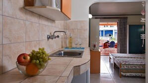 A kitchen with a sink, a bowl of fruit, and a dining area with a table and chairs.