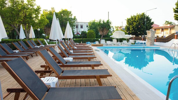 A poolside area with wooden loungers and white umbrellas. - Silver Beach Hotel and Annexe Apartments (Corfu)