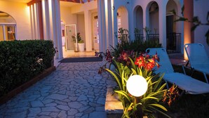A courtyard with a stone pathway, potted plants, and outdoor seating. - Silver Beach Hotel and Annexe Apartments (Corfu)