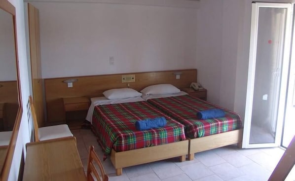 Un lit double avec une couvre-lit à carreaux, une tête de lit en bois, une table de chevet et une chaise.