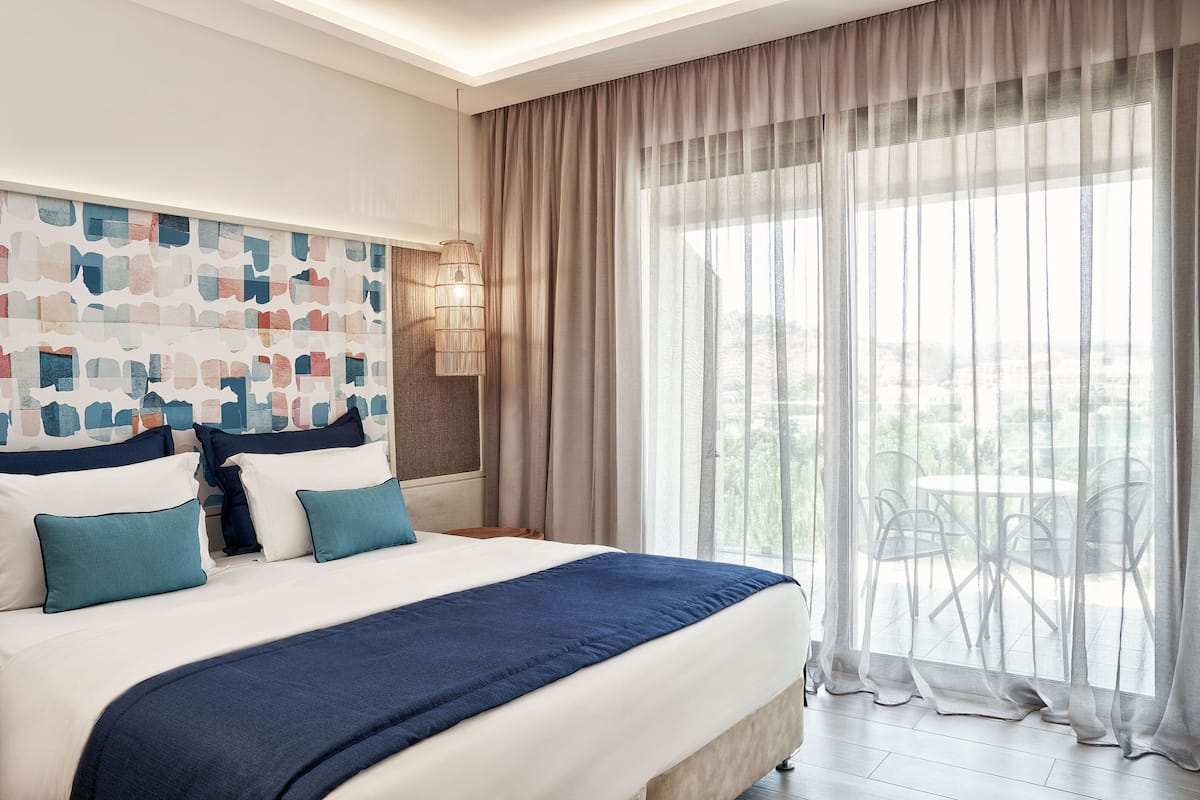 A hotel room with a large bed, a view of the outdoors, and a modern wall design.
