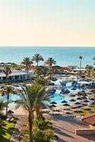 Un resort con varias piscinas, palmeras y vista al océano.