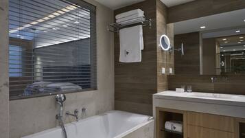 A modern bathroom with a bathtub, a large mirror, and wooden cabinetry.